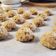 Balls of oatmeal scotchie dough lined up on parchment paper